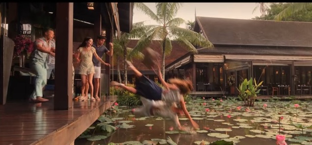 Will and Lana falling into into the pool of water filled with lily pads and blossoms as everyone gasps.